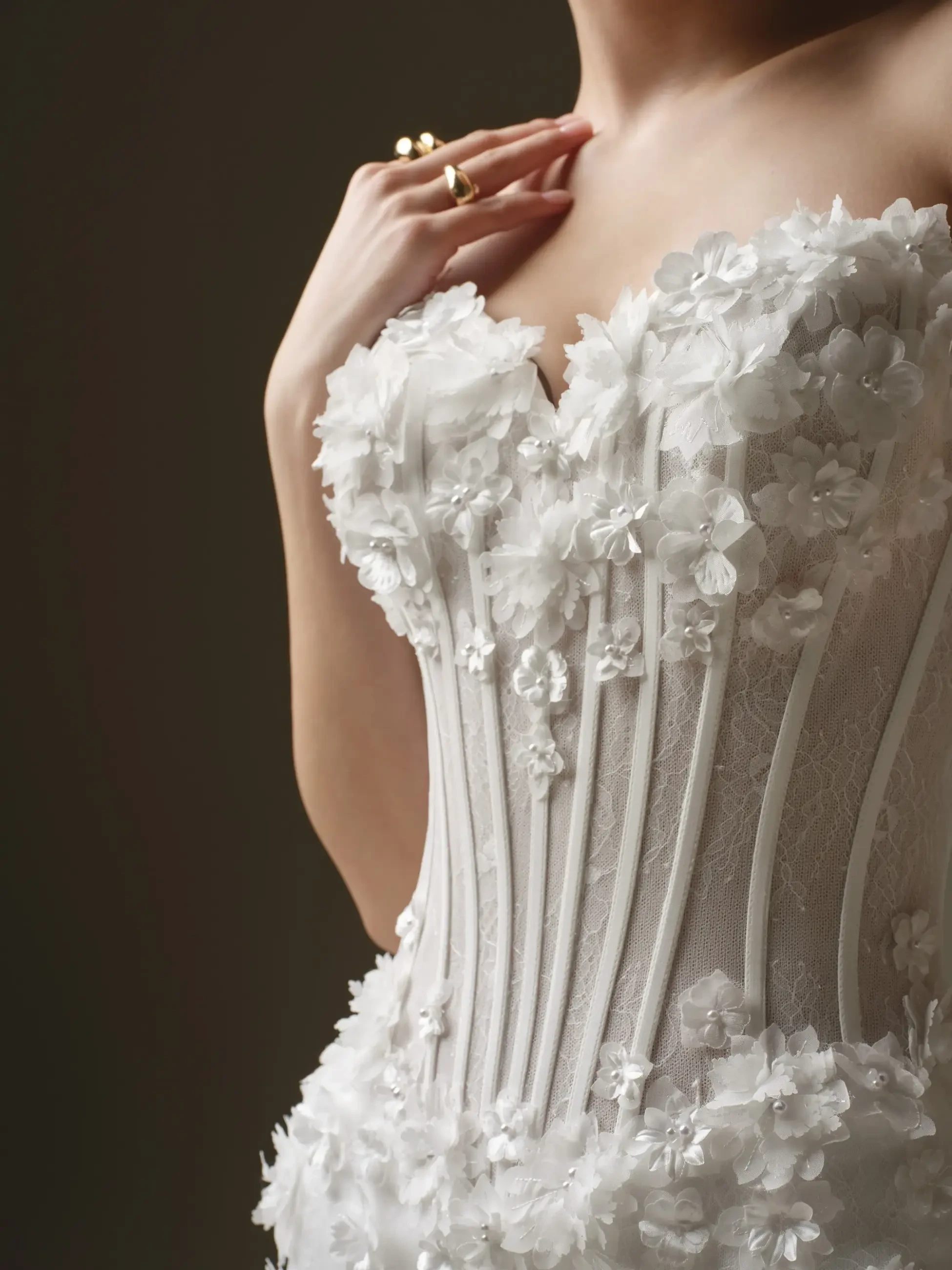 Close-up of a woman's torso in an elegant white lace corset, adorned with delicate floral applique. The mood is romantic and sophisticated.